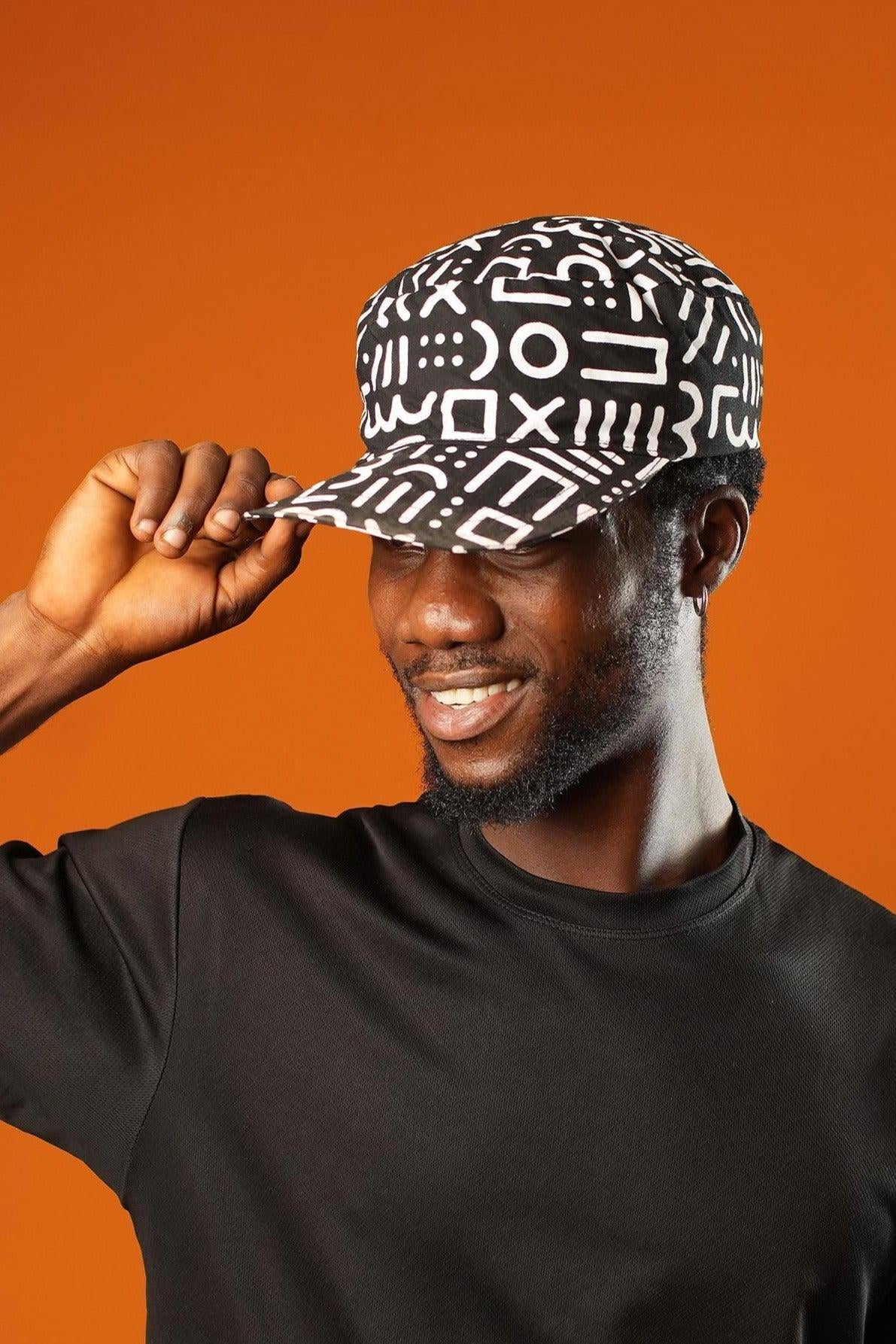 Close-up of a man wearing a Black and White Baseball Cap made from 100%cotton, featuring a Mudcloth Afrocentric print. The unisex cap has a flat brim and bold tribal symbols, styled as a Bohemian Tribal Festival accessory or African Gift.