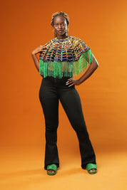 Woman wearing a Green Tassel Cape made from recycled African print fabric, styled as a bold Ankara Cape. This colourful Festival Outfit piece is perfect for Afropunk events, Rave Wear or adding flair to any look—crafted by Ashanti Empress.