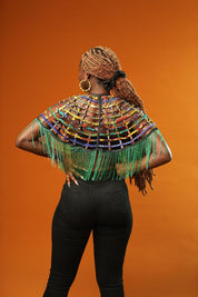Woman wearing a Green Tassel Cape made from recycled African print fabric, styled as a bold Ankara Cape. This colourful Festival Outfit piece is perfect for Afropunk events, Rave Wear or adding flair to any look—crafted by Ashanti Empress.