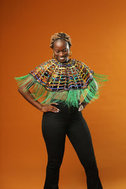 Woman wearing a Green Tassel Cape made from recycled African print fabric, styled as a bold Ankara Cape. This colourful Festival Outfit piece is perfect for Afropunk events, Rave Wear or adding flair to any look—crafted by Ashanti Empress.