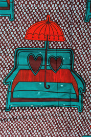 African wax print fabric featuring a playful and romantic design of turquoise blue love seats with red and brown heart-shaped pillows, each topped with a bright red umbrella. The background is a dark brown covered in a pattern of small white teardrop shapes, creating a bold and eye-catching contrast. Perfect for statement fashion or unique home decor projects.