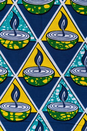Bold African wax print fabric featuring a repeating pattern of green and yellow candle bowls with blue flames, set inside alternating teal and yellow triangles on a dark blue background.
