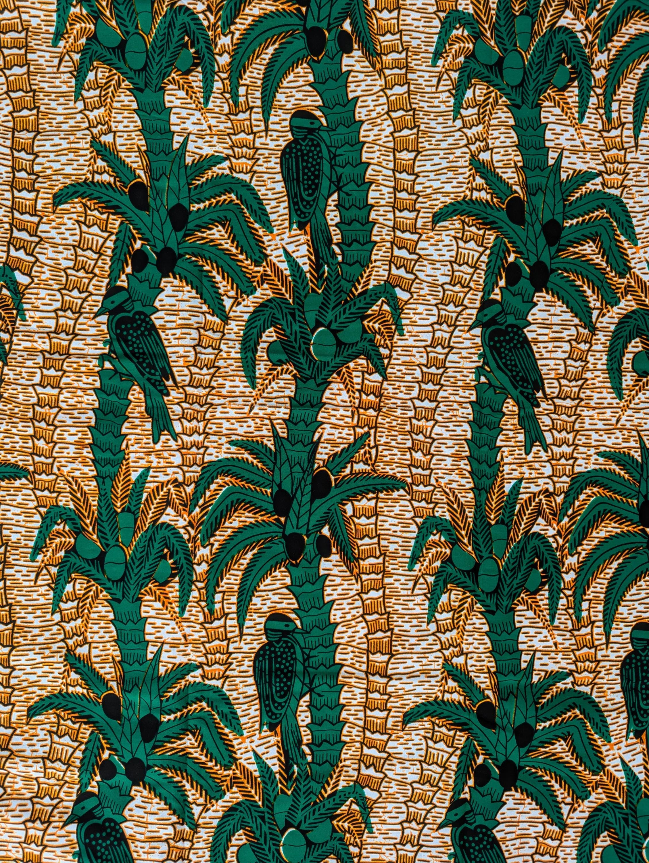 Tropical-themed African wax print fabric featuring green palm trees with coconuts and perched birds, set against a warm background of textured golden-brown lines. The repeating pattern creates a lush, jungle-like feel, perfect for vibrant fashion, home decor, or craft projects.