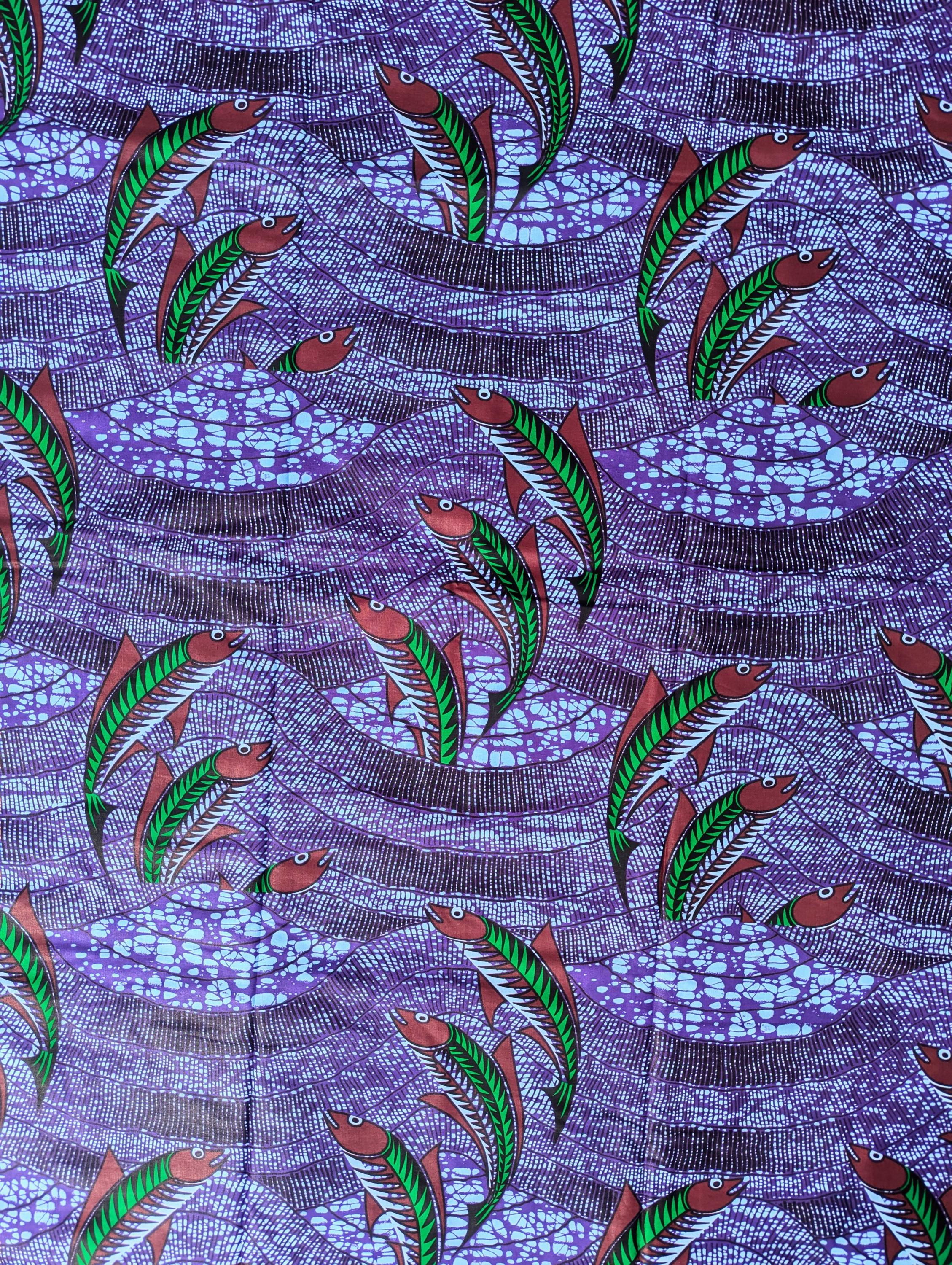 Vibrant African wax print fabric featuring a dynamic underwater scene of green and red fish swimming through wavy purple and blue waters. The background has a textured pattern resembling flowing currents and bubbles, adding movement and depth to the design. Perfect for bold fashion or aquatic-themed crafts.