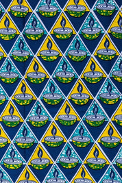 Bold African wax print fabric featuring a repeating pattern of green and yellow candle bowls with blue flames, set inside alternating teal and yellow triangles on a dark blue background.